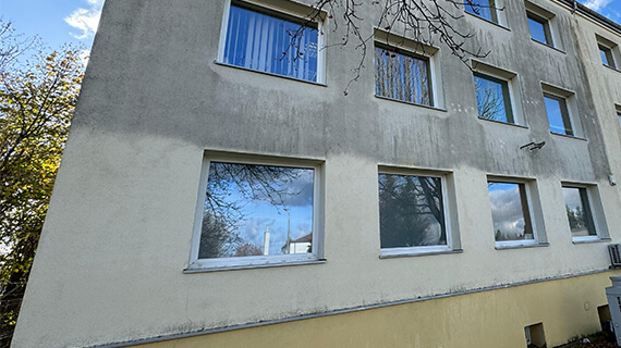 Verschmutzte Putzfassade eines mehrgeschossigen Gebäudes